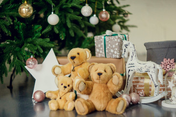 New Year decorations in blue and beige colors. Toy bear, decorative white lanterns and gift boxes under fir-tree. Christmas mood