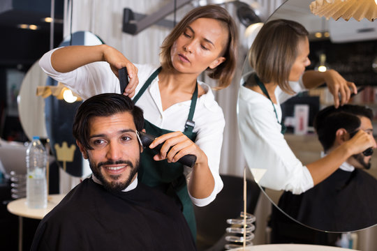 female professional shaving male's hair