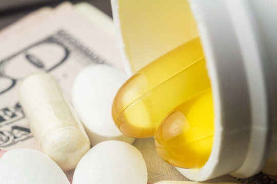 Yellow capsules of omega-3 in bottle, white capsules of glucosamine, white pills of calcium on wooden table, macro image