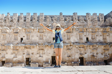 Fototapeta premium Happy woman traveler exploring the ruins of the ancient Greek amphitheater Aspendos in Turkey