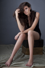 Model in playsuit sitting on wooden box with fashion posing.