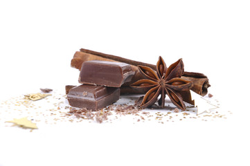 piece of chocolate, anise an cinnamon in confetti and white background