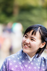 A beautiful young Japanese woman in a kimono looking off of camera.