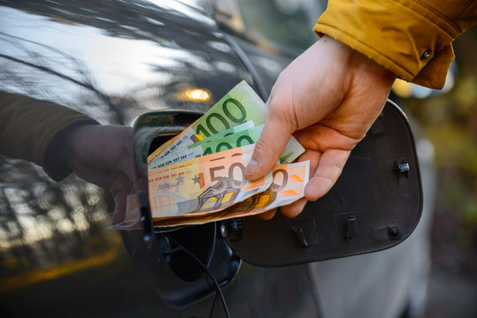 man put money to opening fuel tank of the car