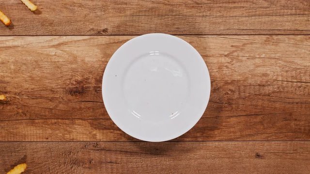 French fries escape from a central plate - leaving in every direction, top view, stop motion animation