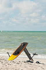 Fototapeta na wymiar Yellow and black kiteboard balanced in the sand and a handlebar at a stormy, windy, autumn day, at a tropical beach off the coast of the Gulf of Mexico