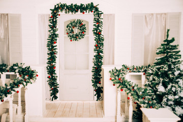 house entrance decorated for holidays. Christmas decoration. garland of fir tree branches and lights on the railing