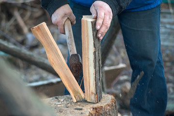 Close-up of men's hands chopping firewood with an ax.