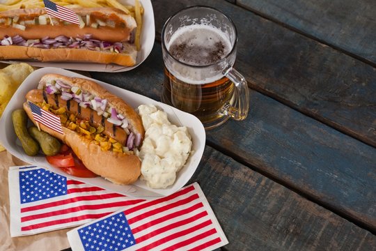 Hot dog and glass of beer with American flag on wooden table