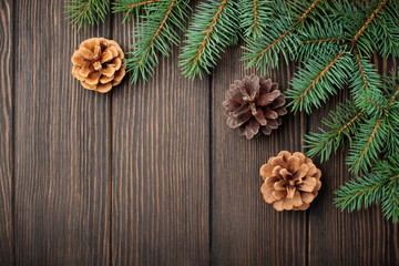 Christmas or New Year background. Fir-tree branches , Christmas tree toys, stars, snowflake and cones on dark brown wooden background. Selective focus. Top view. Copy space.