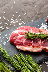 Close up of raw fresh meat with herbs and spices on dark rustic background.