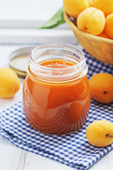 Apricot jam in a glass with apricots on a light background. Copy space.