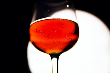 Glass of red wine in back light on black&white background.