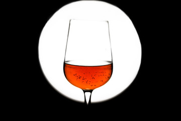Glass of red wine in back light on black&white background.