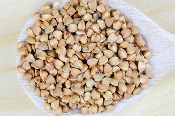 Buckwheat seeds on a wooden spoon.
