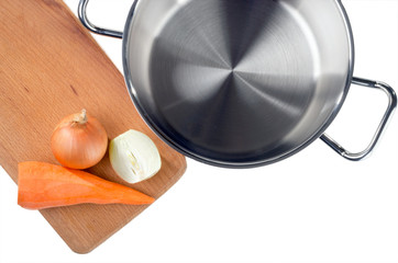 Stainless cooking pot with vegetables on a cutting board isolated on white.