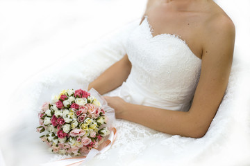 beautiful bouquet of different colors in the hands of the bride in a white dress