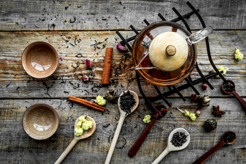 Tea party set. Tea pot, cups, dried tea leaves, fllowers, spices on wooden background top view