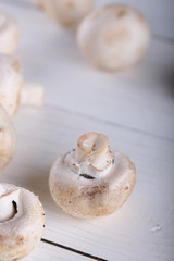 Mushrooms champignons on a white wooden background