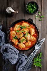 Meatballs in tomato sauce garlic and parsley in an iron frying pan on a dark brown wooden background. Selective focus. Top view. Copy space.