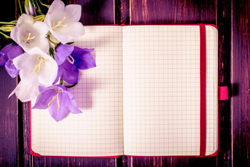 blank note book close-up with spring flowers and copy space on wooden background. summer border template. mock-up floral background. sale, greeting and celebration card concept.