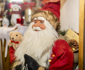 Santa Claus or Father Christmas dummy figure or mannequin on display with a teddy bear next to him in a toy shop window
