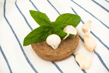 Composition with basil, garlic and cork stopper with striped tablecloth front view