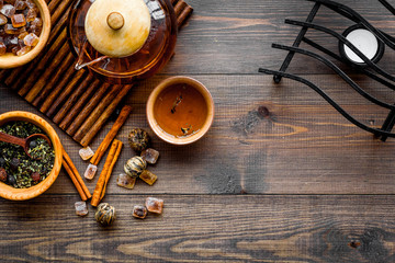Tea ceremony concept. Tea pot, cups, dry tea leaves, sugar on dark wooden background top view copyspace