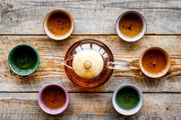 Set for tea ceremony. Glass teapot and ceramic cups on rustic wooden background top view