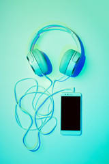Mobile phone (smartphone) and headphones on blue