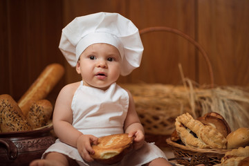 Small child cooks a croissant in the background of baskets with rolls and bread. Copy space
