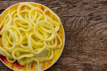 Plate with crispy snacks onion rings on wooden table