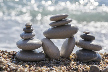 Stones and pebbles stack, harmony and balance, three stone cairns on seacoast with ocean waves on background