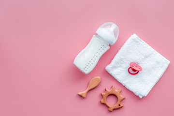 Obraz na płótnie Canvas Little baby background. Wooden toys, pacifier, bottle, towel on pink background top view copyspace