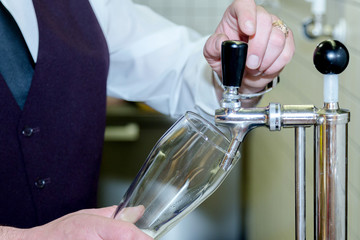 The bartender is gaining the beer into the glass