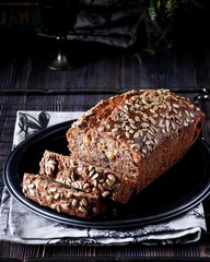 Banana cake with seeds and raisins on a metal dish and cotton napkins. Wooden table. Dark background