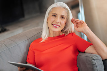 Happy smile. Cheerful pleasant elderly woman smiling and looking at you while resting at home