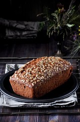 Banana cake with seeds and raisins on a metal dish and cotton napkins. Wooden table. Dark background