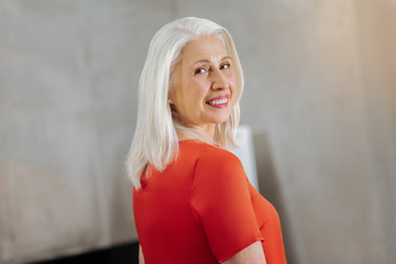 Fototapeta premium Positive smile. Joyful attractive delighted woman smiling and looking at you while being in a positive mood