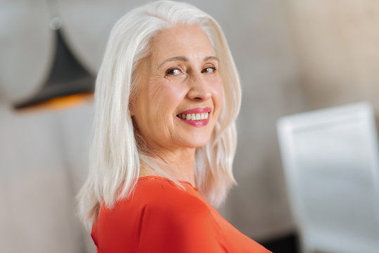 Being friendly. Cheerful aged positive woman turning to you and smiling while being open and friendly