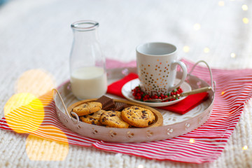 Glass with milk and oatmeal cookies with chocolate chips close-up on white tray