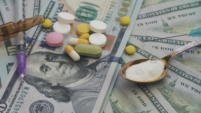 Drugs and pills for addiction lie on the thousands of paper dollars 