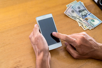 hand with phone and dollars on desk