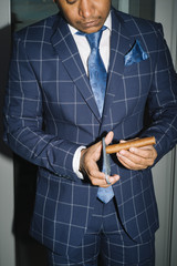elegant man wearing suit and white shirt cut Cuban cigar indoor shot, closeup, selective focus