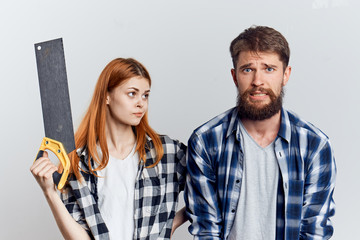 Young beautiful woman on white isolated background with bearded man holding a saw, repair