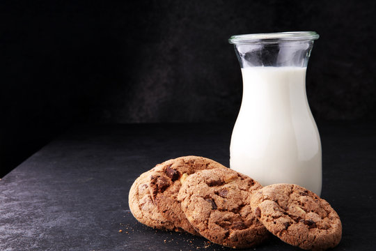 Chocolate chip cookies with milk on dark grey table