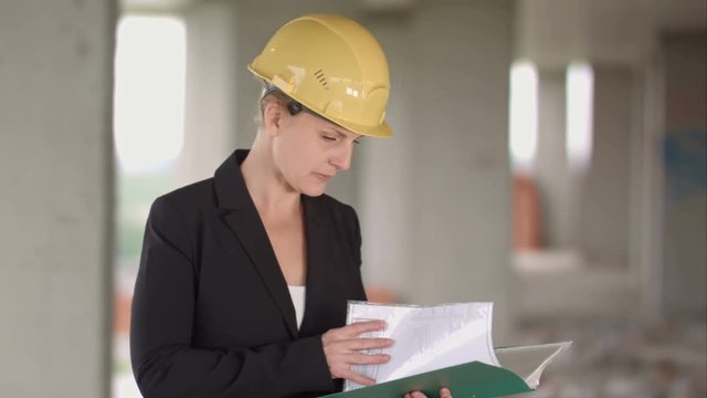 Female architect looking at blueprints at construction site