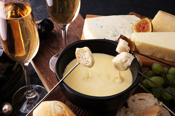 Gourmet Swiss fondue dinner on a winter evening with assorted cheeses on a board alongside a heated...