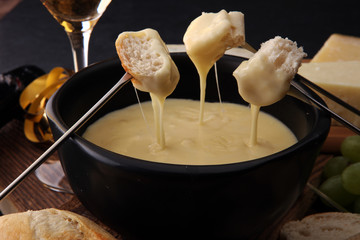 Gourmet Swiss fondue dinner on a winter evening with assorted cheeses on a board alongside a heated...