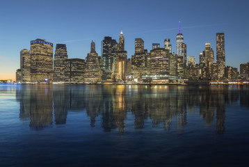 Manhattan skyline reflected in the water of the East River.